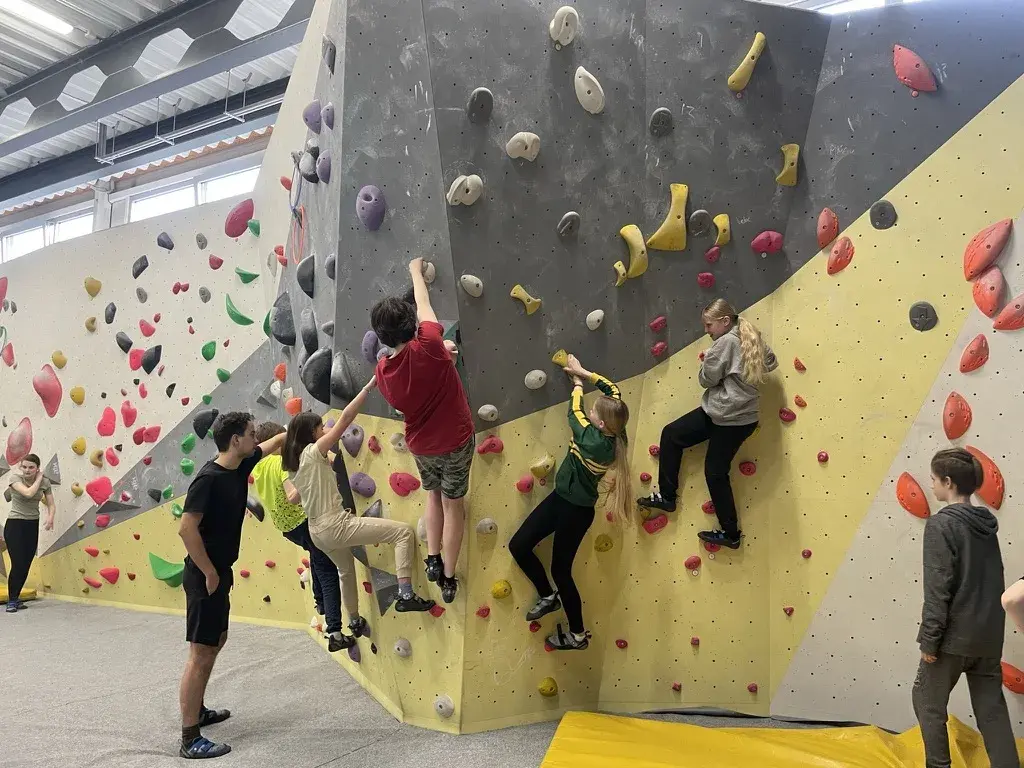 Dorostenci společně lezou na boulderingové stěně